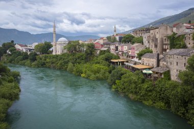 Mostar, Bosna-Hersek - 20 Mayıs 2016: Koski Mehmed Paşa Camii ve Neretva Nehri. Eski kasaba 1993 yılındaki Hırvat-Boşnak savaşı sırasında yıkıldı, yeniden inşa edildi ve şimdi bir Dünya Mirası Unesco sahası oldu.