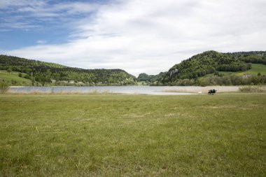 Brenet Gölü ve Jura dağının manzara yaşlı adam ve kadın bir bankta oturan ve bir kuğu besleme çift ile, Le Pont, İsviçre