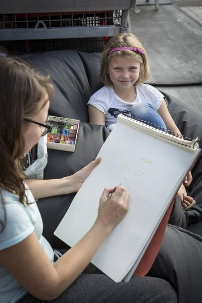 Amsterdam, The Netherlands, 12-14 September 2014, at West'ival, a free open air Cinema and culture festival on Mercatorplein. artist sketching a little girl