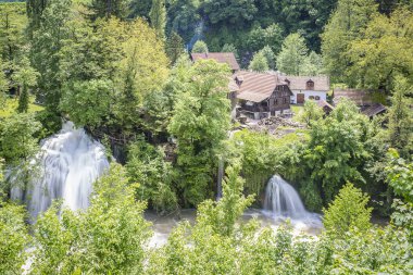 Ağaçlar ve bir şelale ile yeşil bir manzara ahşap evler ile bir nehir kanyon u Rastoke Hırvat köyü, Hırvatistan