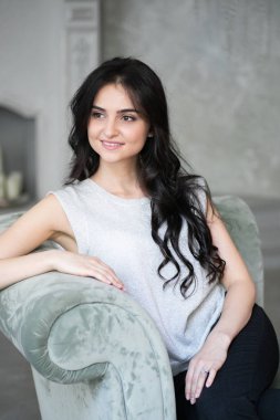 Seks, baştan çıkarma, iş, iş, başarı, stil, liderlik, yönetim, girişimci sembolü olarak gri koltukta oturan çekici esmer işkadını.