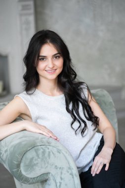 Seks, baştan çıkarma, iş, iş, başarı, stil, liderlik, yönetim, girişimci sembolü olarak gri koltukta oturan çekici esmer işkadını.