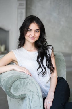 Seks, baştan çıkarma, iş, iş, başarı, stil, liderlik, yönetim, girişimci sembolü olarak gri koltukta oturan çekici esmer işkadını.