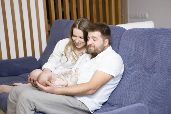 happy family playing with newborn twins at home.  Parent and children relaxing together on the sofa at home in the living room