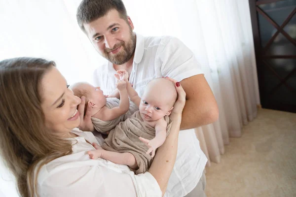 evde yeni doğan ikizler ile mutlu bir aile. Anne-baba ve çocukların birlikte evde oturma odasında kanepede rahatlatıcı