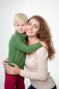 Açık gri arka planda çocuğu olan mutlu genç bir anne.