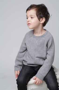 Gri stüdyo arka planda ayakta genç duygusal yakışıklı çocuk. İnsan duyguları, yüz ifadesi konsepti.