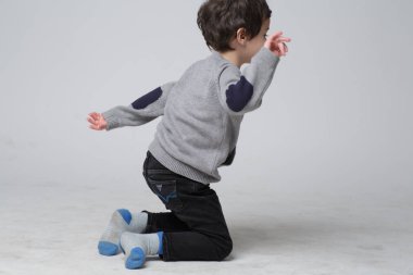 Gri stüdyo arka planda ayakta genç duygusal yakışıklı çocuk. İnsan duyguları, yüz ifadesi konsepti.