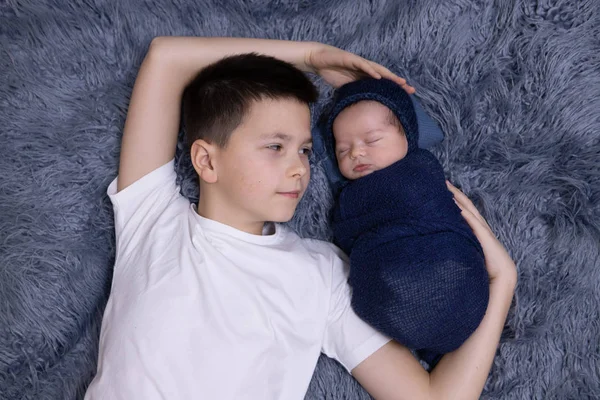 Küçük kardeşi yeni doğan bebeğine sarılıyor. Yeni bir kardeşle tanışan küçük çocuk. Evde çocuklu bir aile. Sevgi, güven ve şefkat