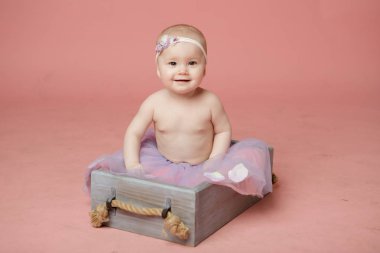 Sevimli küçük yenidoğan bebek prenses bir sepet içinde, mutlu gülümseyerek ve kamera bakarak, izole stüdyo çekim