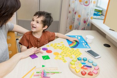 Ev okulu kavramı, uzak eğitim, aile, gelişme. Annesinin çocuğu geometrik şekillerle, harflerle, saatle oynuyor. Hareket, anneye bak. Yaşam tarzı. Seçici odak.