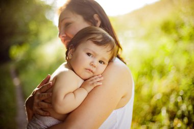 Annenin yakın portresi açık havada kızına nazikçe sarılıyor. Akşam doğal ışık.