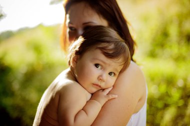 Annenin yakın portresi açık havada kızına nazikçe sarılıyor. Akşam doğal ışık.