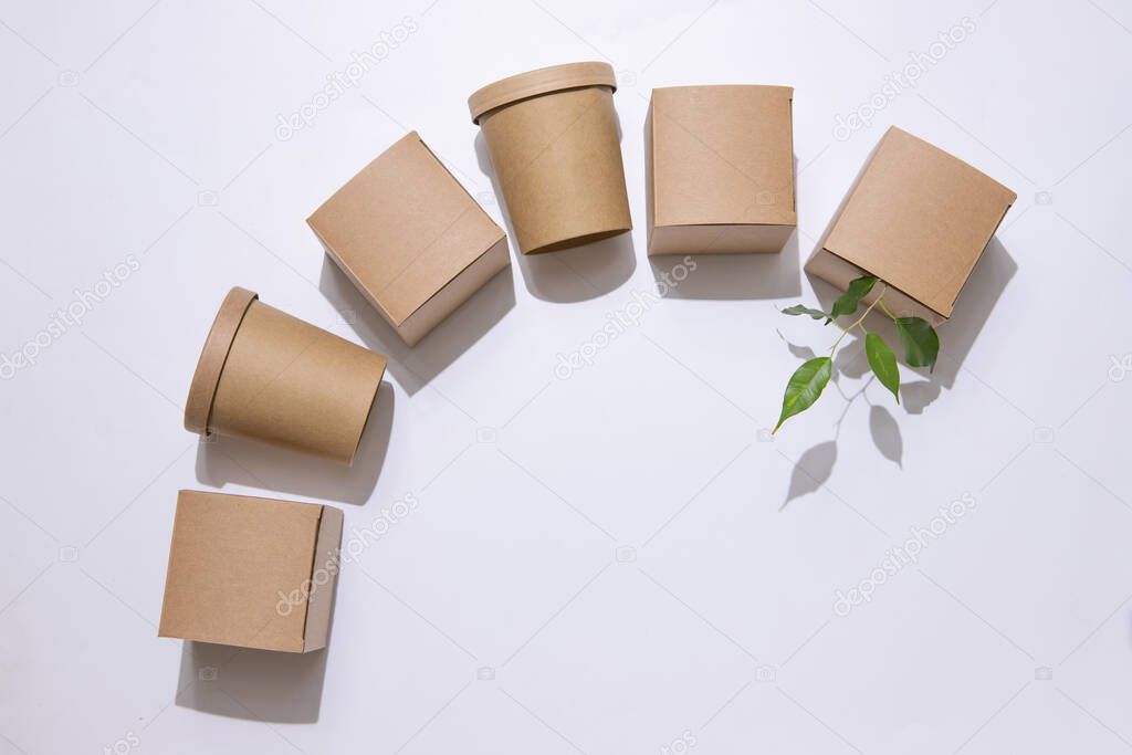 Delivery concept, takeaway, packaging, save the earth. Cardboard boxes for food, drinks and objects. Square and round. Green leaves. White background. Isolate Top view.