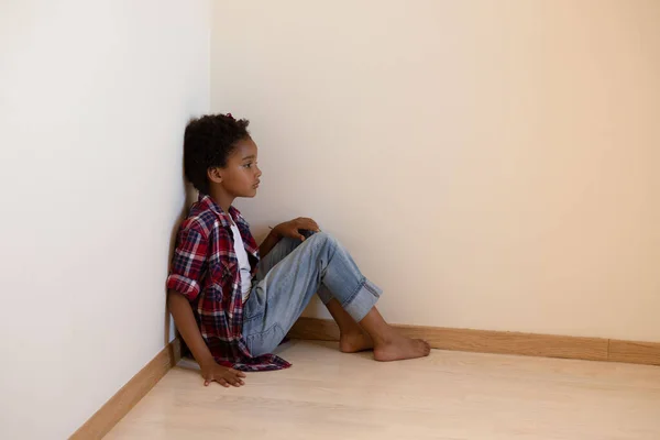 Karışık ırktan mutsuz bir çocuk köşede oturuyor. Üzgün surat. Afro saç. Yalnızlık, ayrılık, istismar kavramı. Yatay olarak. Boşluğu kopyala. 