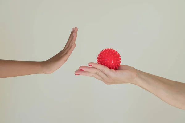 Red ball with spikes is a symbol of the Covid 19 virus in the hand of an adult, which passes it to the child.  Gesture of protection. Hygiene concept, the possibility of infection with the virus.