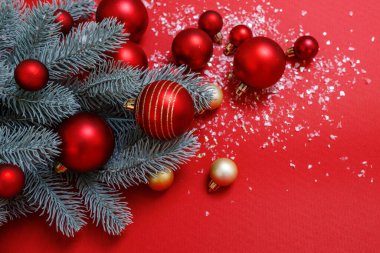 Kırmızı ve yeşil yılbaşı arkaplanı. Şenlikli dekoratif kompozisyon Noel ağacı, büyük ve küçük kırmızı ve altın toplar, yapay kar. Üst Manzara. Hiç kimse. Yatay, mesaj için yer. Mutlu yıllar teması