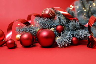 Kış tatili konsepti. Kırmızı, altın Noel süslemeleri kırmızı arka planda, Noel ağacı ve ışık var. Bayramlık Noel kartı. Planlar için mutlu yıllar teması. Mesaj için yer var. Yatay