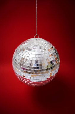 Kırmızı arka planda ayna disko topu. Dikey. Disko ve parti sembolü. Dikey. Seçici odak.