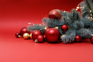 Kış tatili konsepti. Kırmızı, altın Noel süslemeleri kırmızı arka planda, Noel ağacı ve ışık var. Bayramlık Noel kartı. Planlar için mutlu yıllar teması. Mesaj için yer var. Yatay