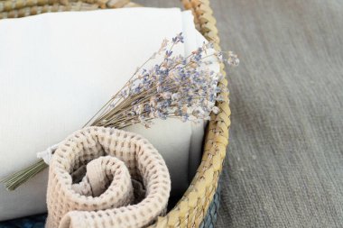 Rahat bir ev için dekorasyon. Güzel eşyalar. Yuvarlak havlu, katlanmış bej kumaş, sepetteki lavanta buketi. Kapatın. Hiç kimse. Yatay olarak. Kokular, spa, provence tarzı.