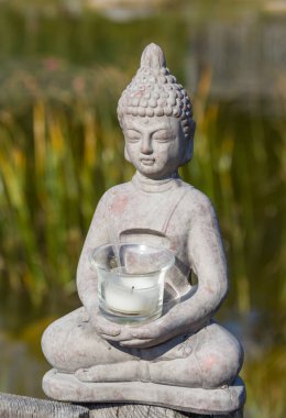 Buda heykeli doğal arka planda. Parkta güneşli bir sabah. Meditasyon ve rahatlama için yaz arkaplanı. 