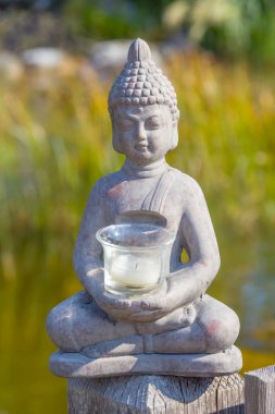 Buda heykeli doğal arka planda. Parkta güneşli bir sabah. Meditasyon ve rahatlama için yaz arkaplanı. 