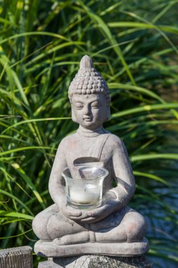 Buda heykeli doğal arka planda. Parkta güneşli bir sabah. Meditasyon ve rahatlama için yaz arkaplanı. 