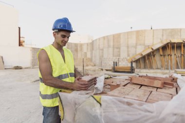 Endüstriyel şantiye inşaatında tuğlalı genç inşaat işçisi