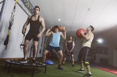 Spor salonunda bir sürü nesneyle birlikte eğitim veren bir grup insan
