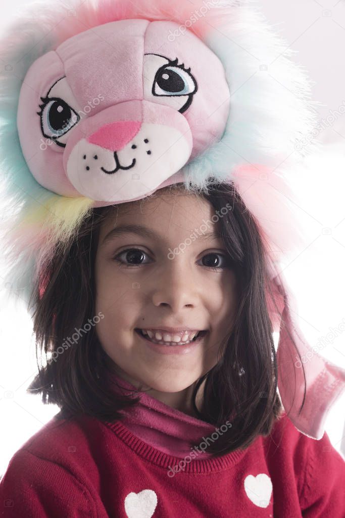 Cute girl portrait with lion muppet hat looking at camera isolated on white