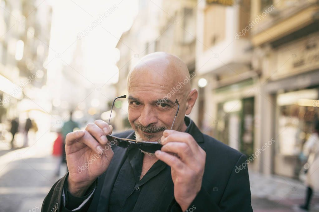 Senior man in the street with sunglasses looking at camera smiling