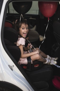 araba sandalyesinde ballons ile sevimli küçük kız çok heyecanlı ve mutlu kameraya bakarak