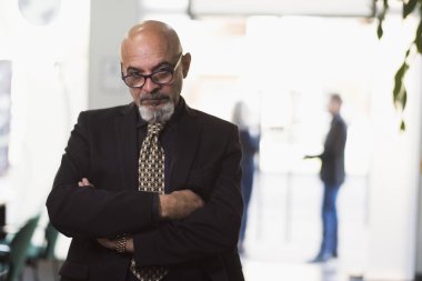 Ofiste Olgun patron poz ve arka plan pencerelerinde insanlarla kamera bakıyor