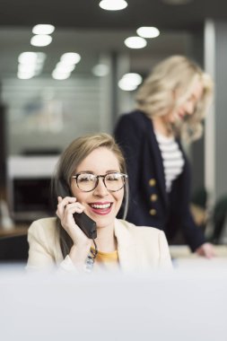 Çekici 30s kadın telefon ve arka planda diğer ofiste çalışan