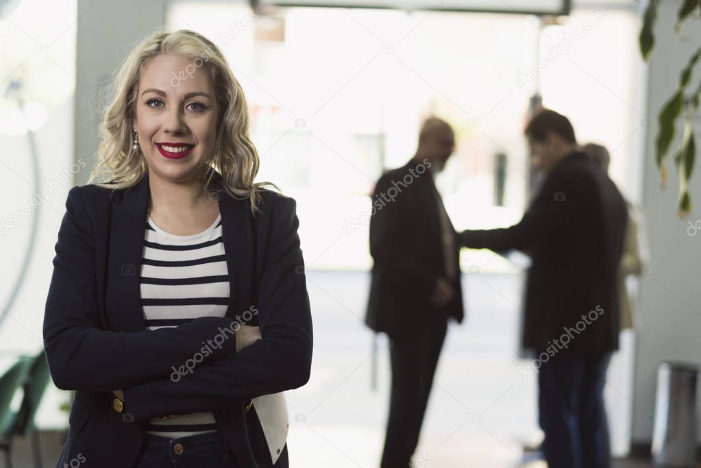 Office woman looking at camera and smiling with people in background