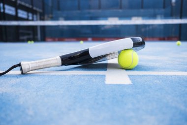  Raket ve padel top mavi sahada.