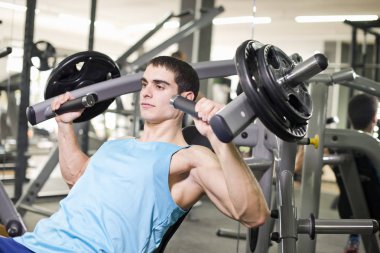 Genç adam spor salonunda ağırlık kaldırma