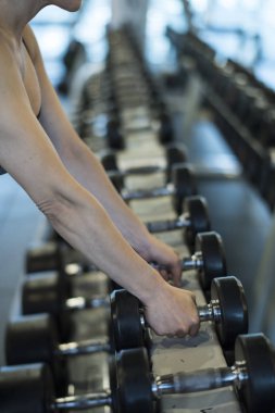 Kadın spor salonunda ağırlık kaldırıyor ve kaslarını çalıştırıyor.