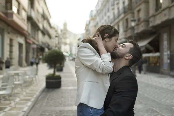 Uomo baciare donna in strada mentre trasporta il suo abbraccio — Foto Stock