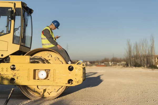 Trabajador Construcción Mirando Smartphone Vehículo Rodillo Vapor Reposo — Foto de Stock