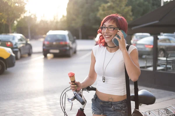 Young woman with ride bike in the city and eats ice cream in summer
