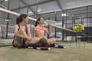 Paddle tenis oyuncuları ders sırasında su içme ve dinlenme
