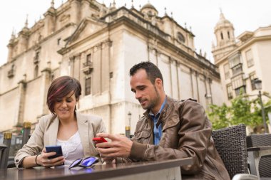 Bar terasında akıllı telefonları olan genç bir çift.