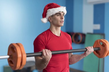 Genç fitness Noel Baba spor salonunda ağırlık kaldırma eğitimi alıyor.