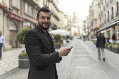 Akıllı telefon ile şehirde adam kamera bakıyor