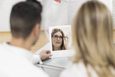 Gözlükçü gözlük mağaza çift ayna ile modelleri çalışıyor