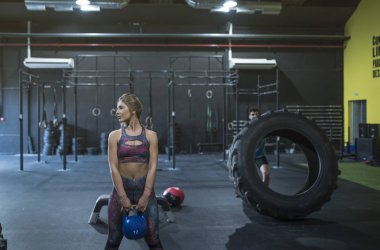 Güzellik sarışın kadın kettlebell ve egzersizler için tekerlek ile adam için hazır  