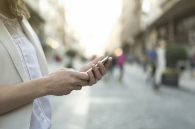 Şehirde akıllı telefon arayan bir kadın var.