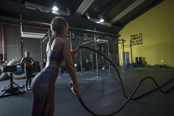 Young woman training in health club with rope